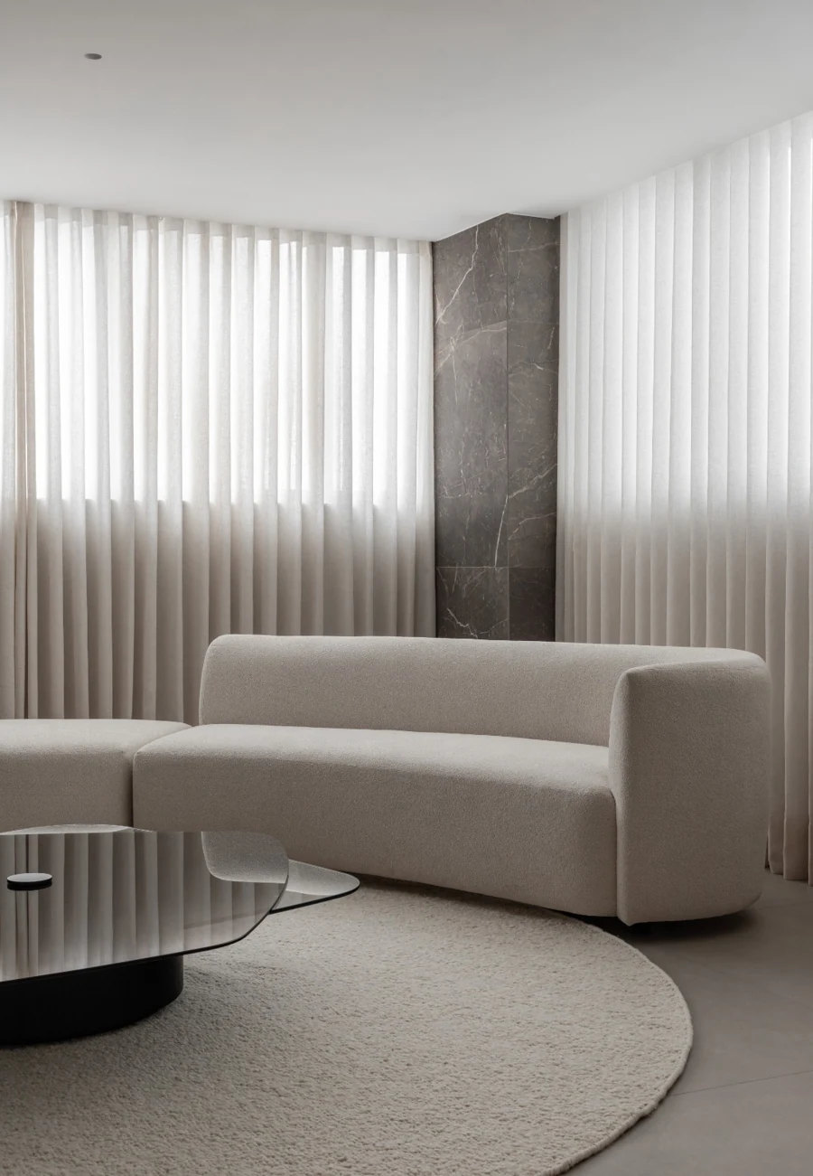 Sala de espera do consultório, com sofá claro, mesa de centro e cortinas