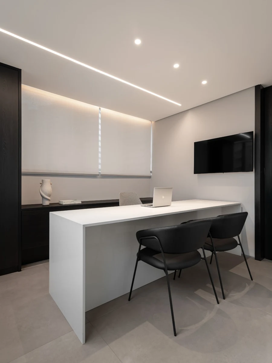Sala de consulta com mesa de atendimento e cadeiras para paciente e acompanhante